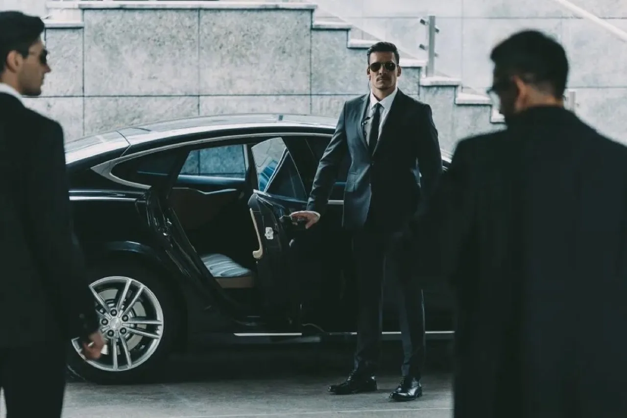Executive protection bodyguard in suit with sunglasses and earpiece at Canadian event