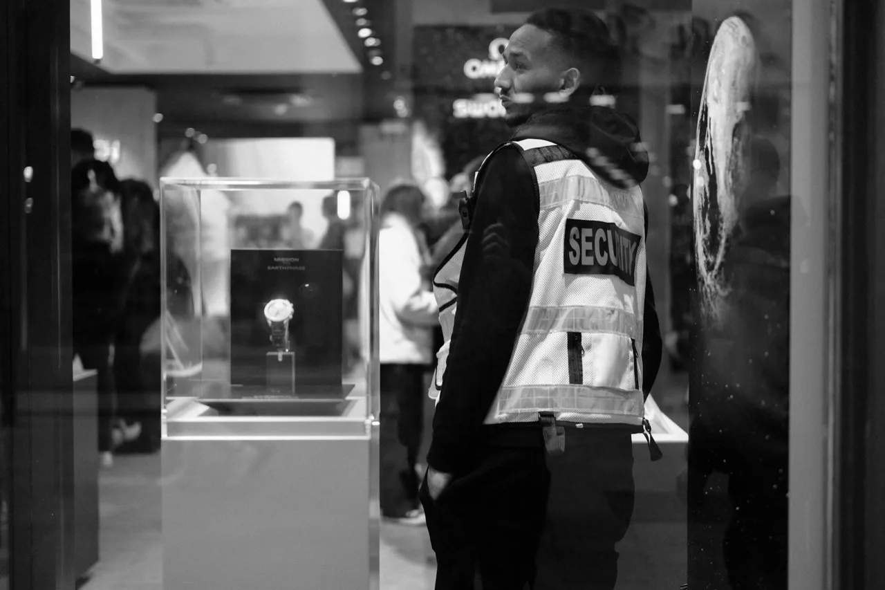 Loss prevention security officer in SECURITY vest monitoring luxury retail display in Canadian store